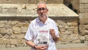 Fernando Pastor sosteniendo el libro Cerrato Insólito frente a una pared de piedra