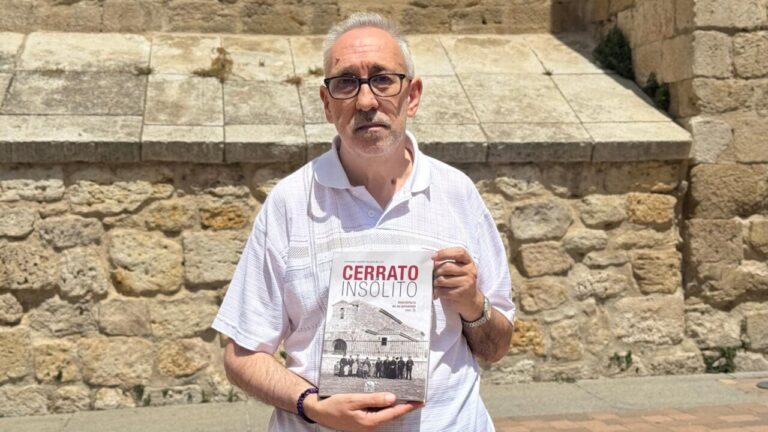 Fernando Pastor sosteniendo el libro Cerrato Insólito frente a una pared de piedra