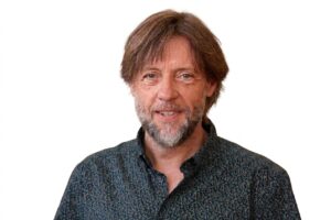 Retrato de Fran Fernández con fondo blanco, sonriendo y con camisa oscura.