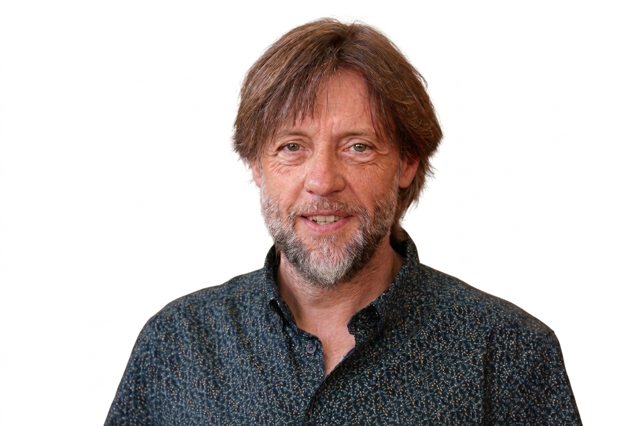 Retrato de Fran Fernández con fondo blanco, sonriendo y con camisa oscura.