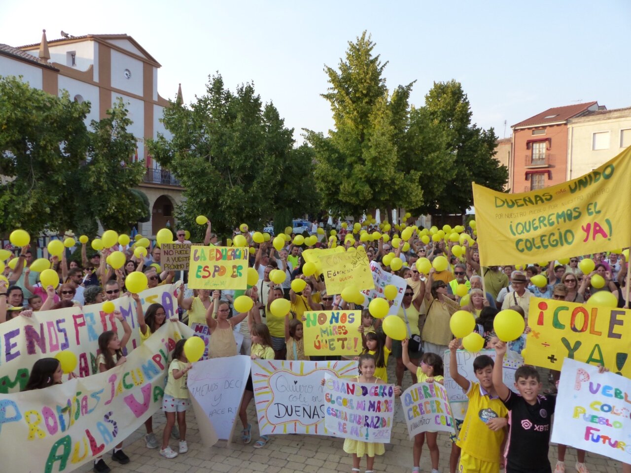 Concentración en Dueñas con globos amarillos y pancartas por un nuevo colegio