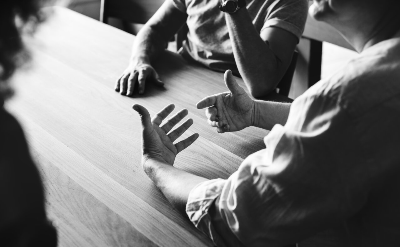 Manos gesticulando durante una conversación en una mesa