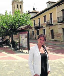 Mujer en una plaza de Fuentes de Nava con edificios y un campanario al fondo