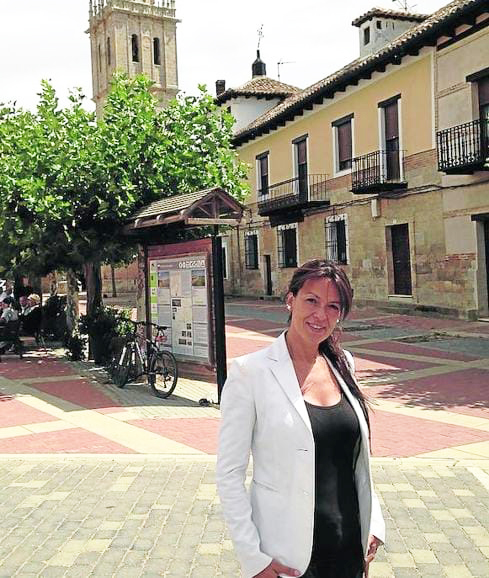 Mujer en una plaza de Fuentes de Nava con edificios y un campanario al fondo