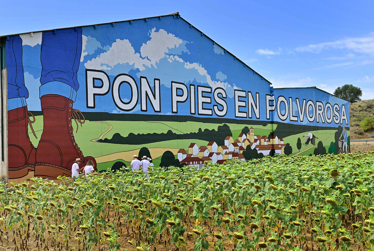 Mural colorido que dice 'Pon pies en Polvorosa' con paisaje rural