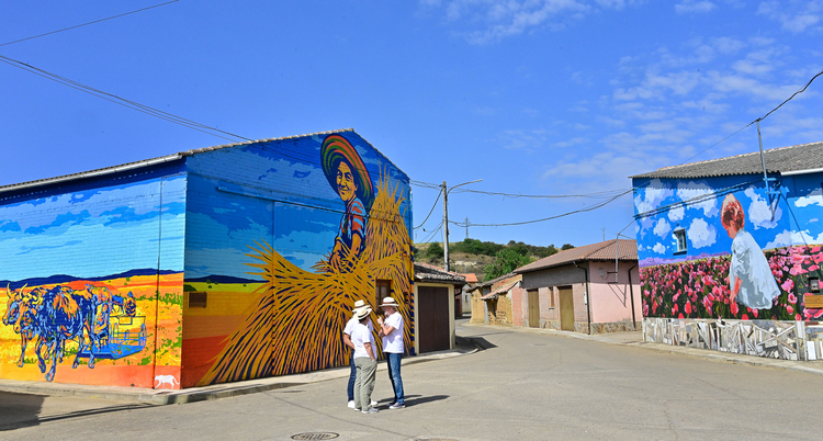 Dos personas observando murales coloridos en Polvorosa de la Valdavia