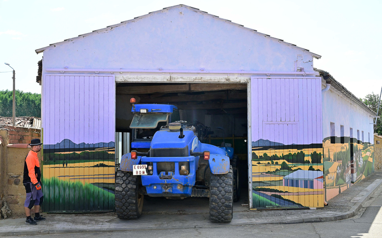 Garaje con tractor azul y mural en la pared exterior