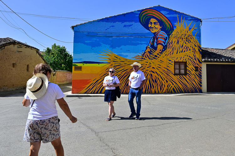 Mural colorido de una persona en un campo con tres personas caminando