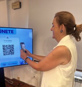 Mujer escaneando un código QR del canal de WhatsApp del PP de Palencia