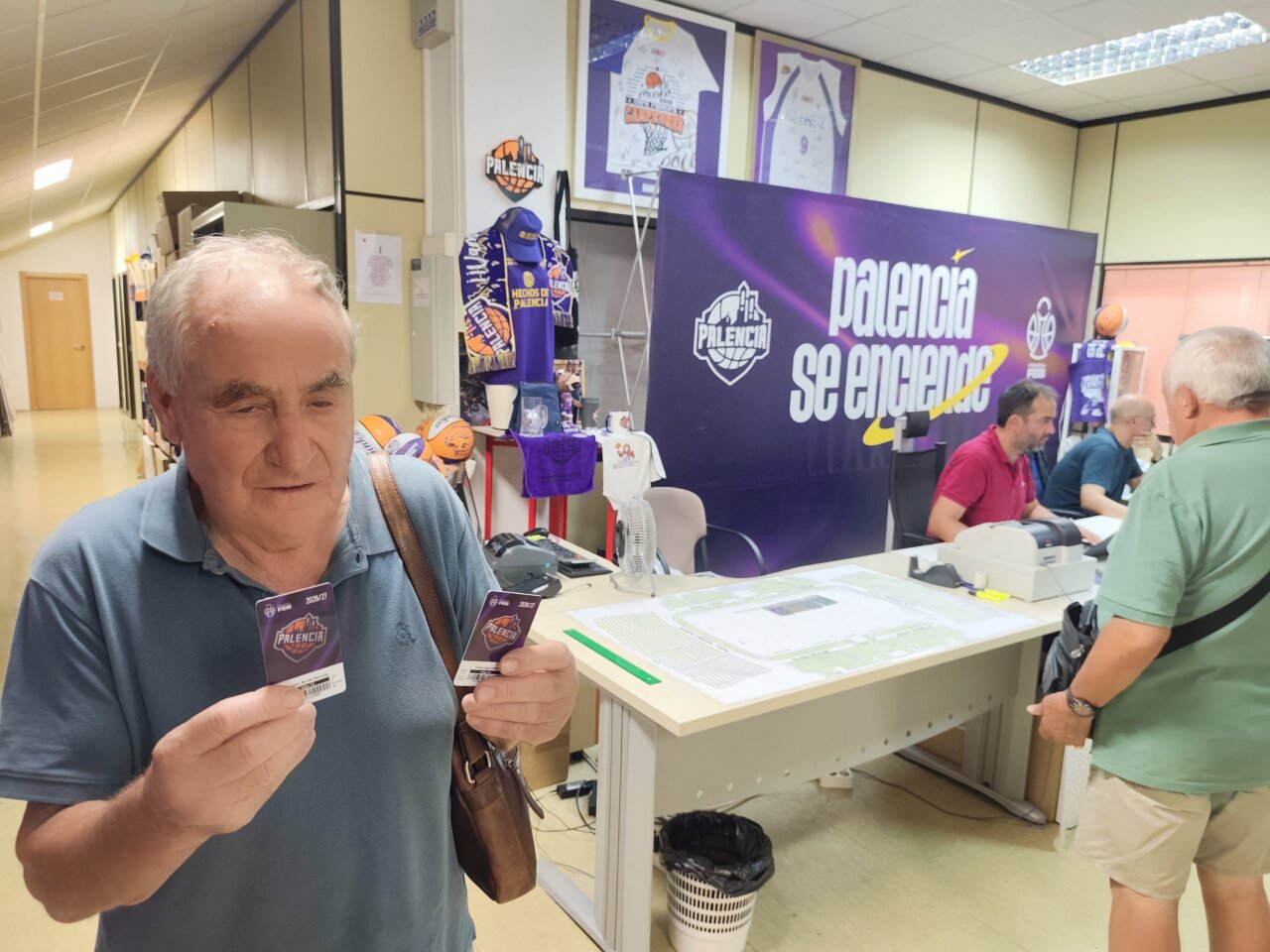 Hombre sosteniendo dos carnés de abono en oficina de Palencia Baloncesto