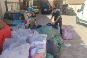 Agente de la Guardia Civil revisando ropa falsificada en un mercadillo.