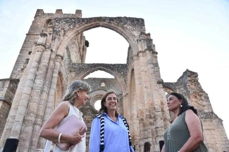 Tres mujeres conversando frente a las ruinas de la iglesia de Santa Eulalia en Palenzuela