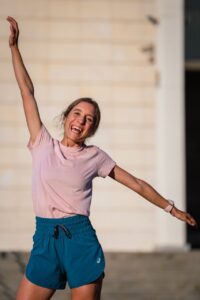 Sara García sonriente en su ropa de atletismo, levantando un brazo.