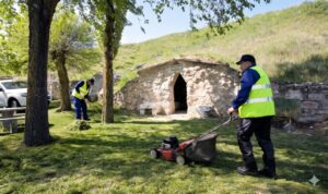 Trabajadores municipales realizando labores de jardinería con maquinaria en un parque