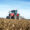 Tractor agrícola rojo trabajando en un campo cultivado bajo un cielo azul