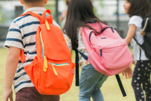 Niños caminando juntos con mochilas hacia la escuela