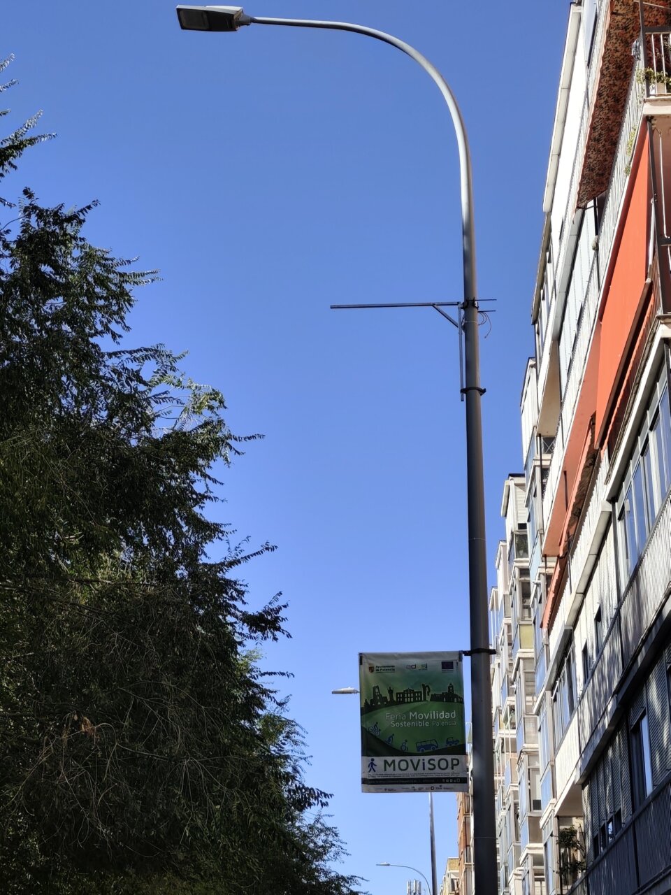 Farola con cartel de Feria de Movilidad en Palencia bajo un cielo azul