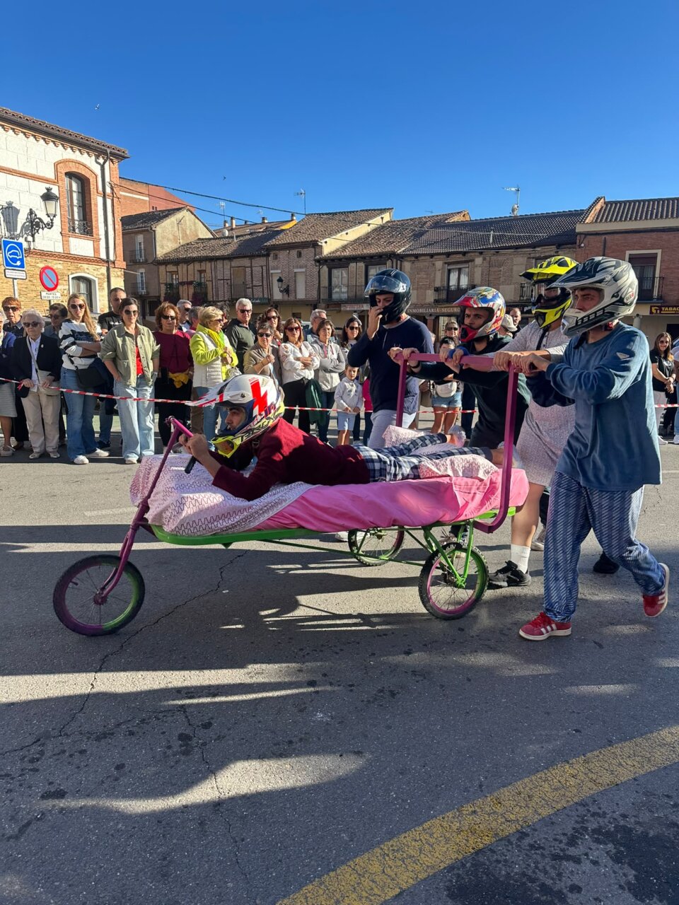 Participantes compiten en la carrera de camas en Saldaña con disfraces y casco