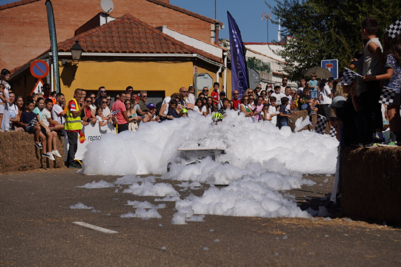 Carrera de autos locos con espuma en Palencia, espectadores animando.