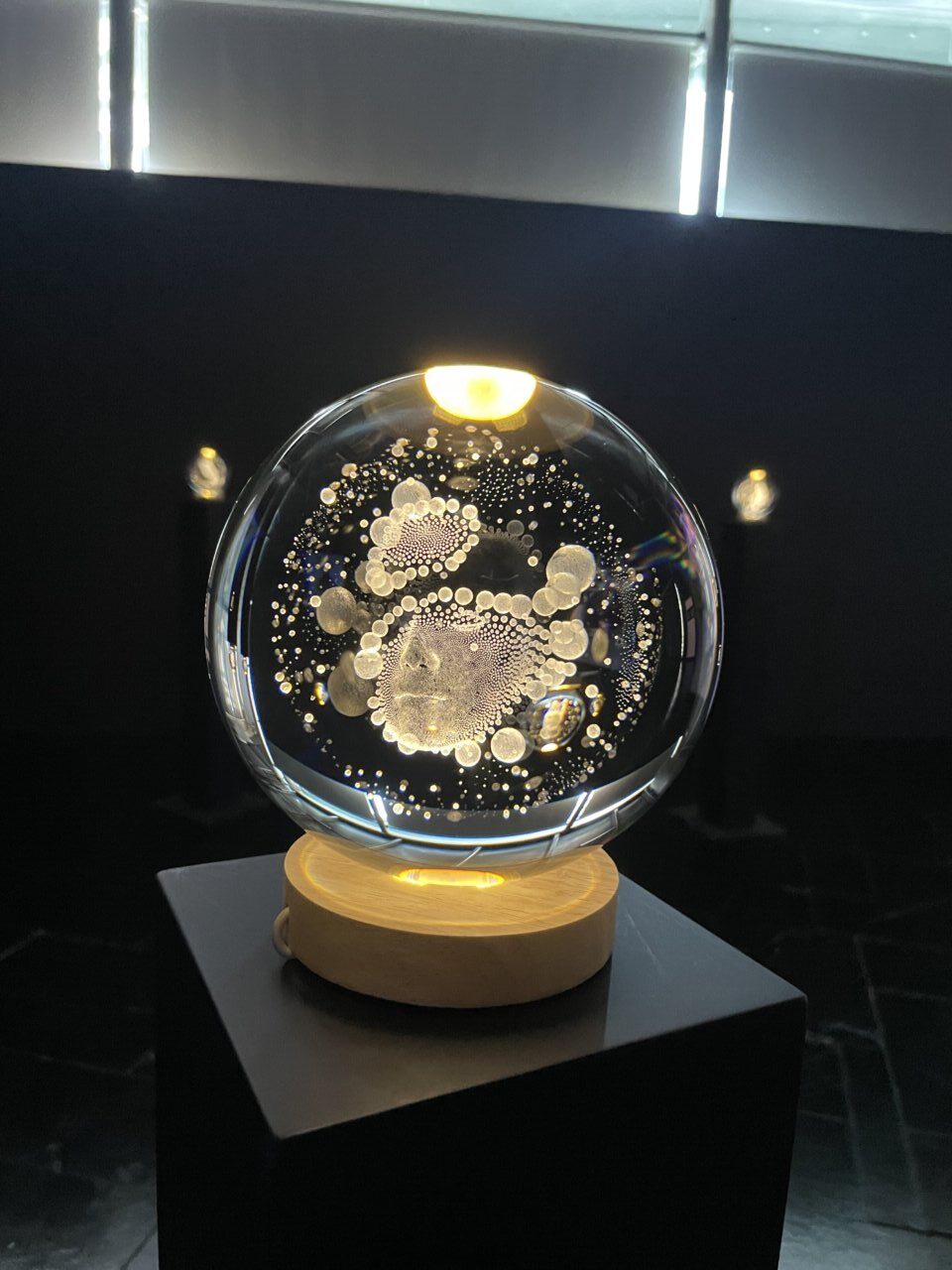 Esfera de cristal iluminada con burbujas y rostros humanos en el museo