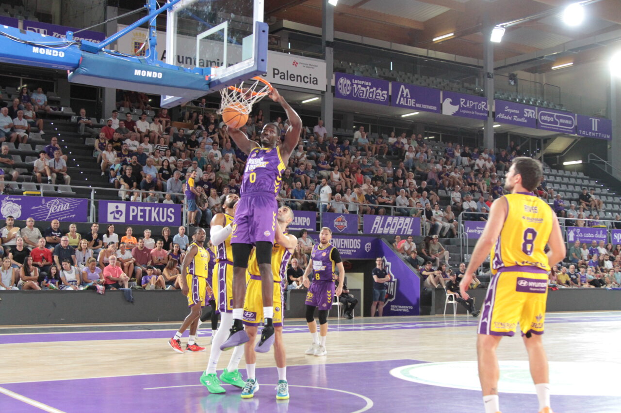 Jugador de baloncesto realizando un mate durante un partido en Palencia