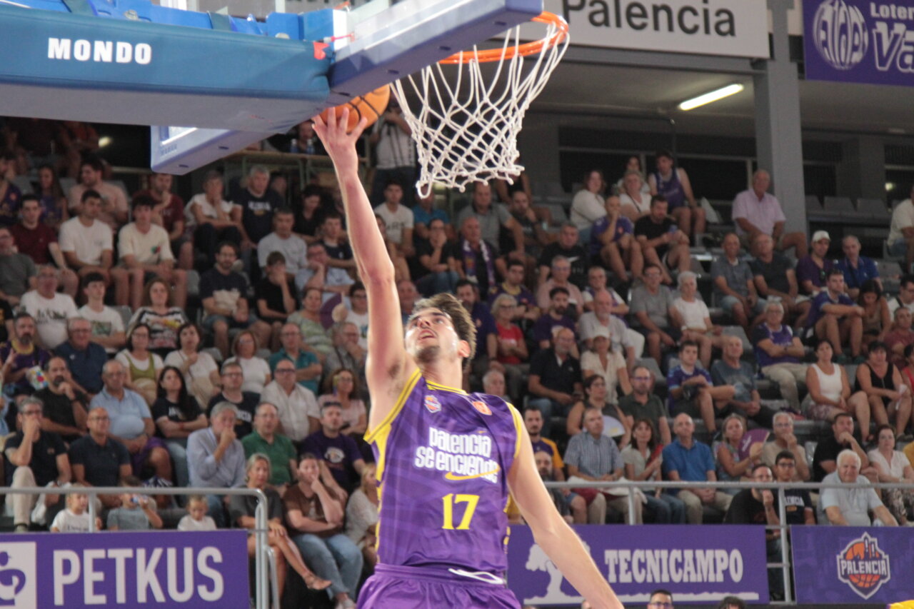 Jugador lanzando el balón hacia la canasta en un partido de baloncesto