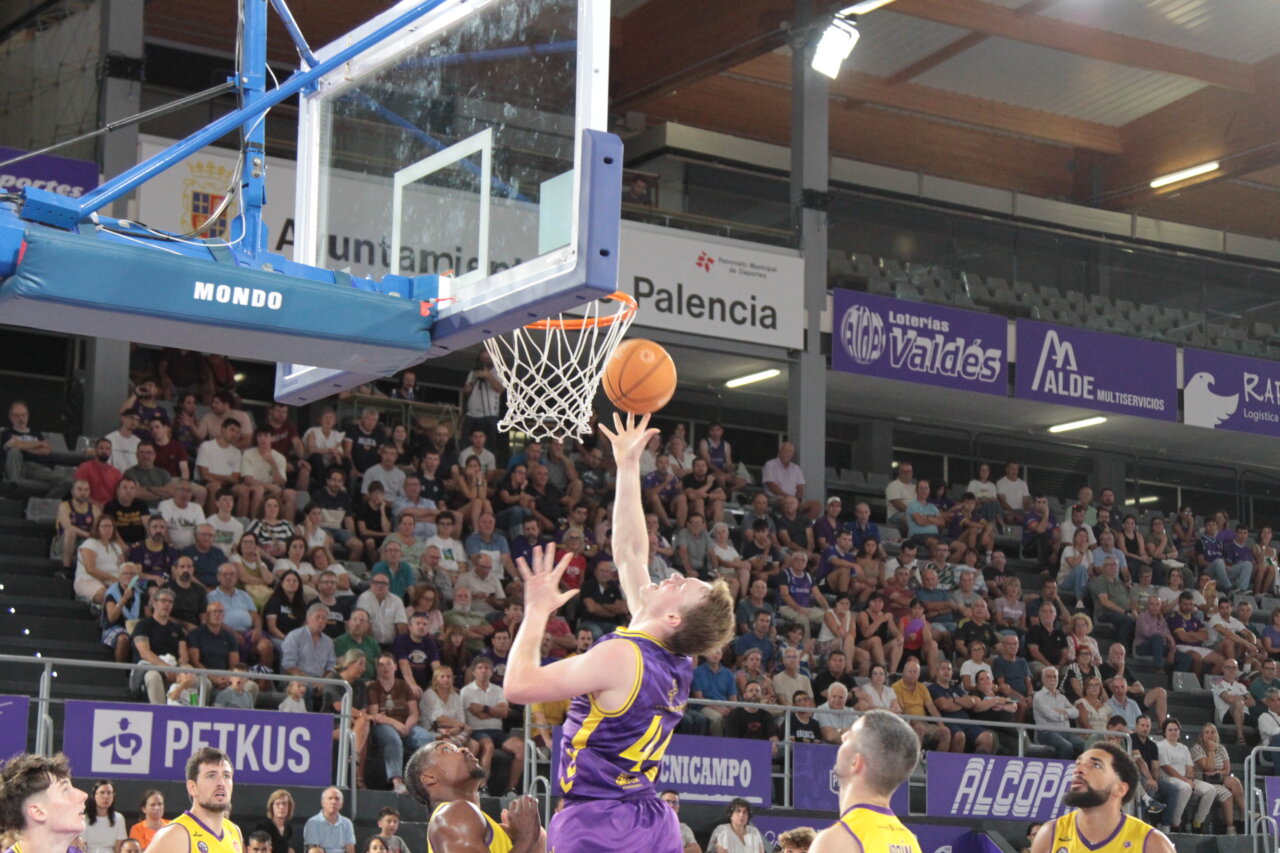 Jugador lanzando a canasta durante un partido de baloncesto en Palencia