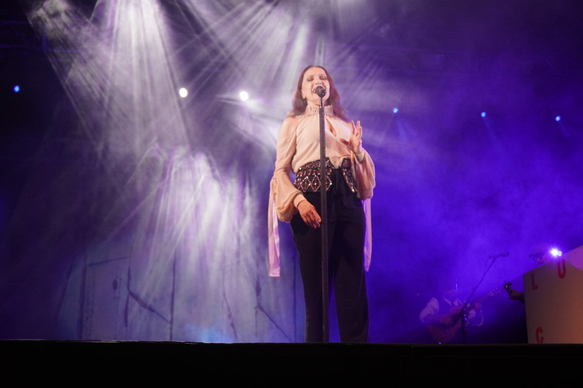 Luz Casal cantando en un concierto con luces de escenario