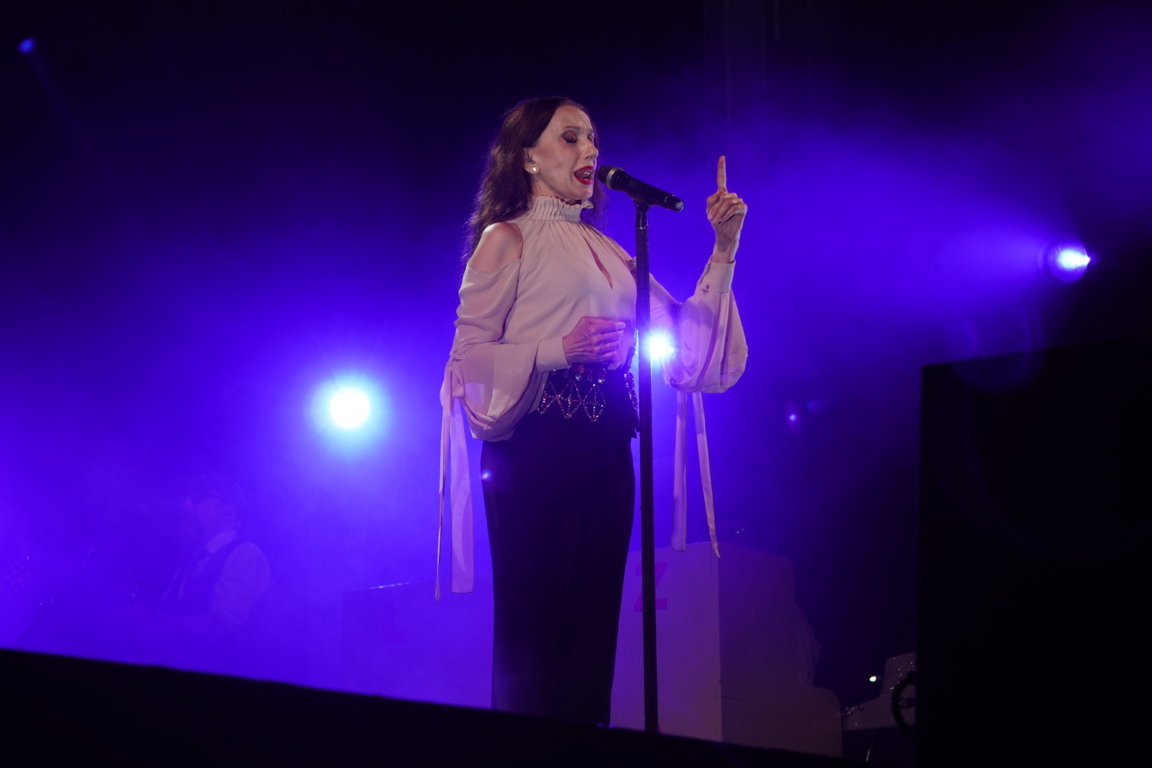 Luz Casal cantando en un concierto con luces de fondo