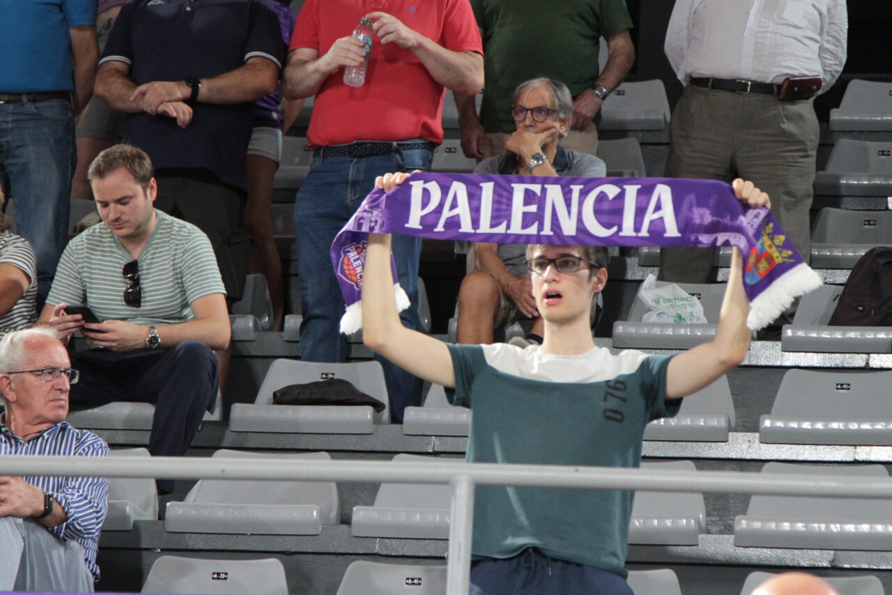 Aficionado sosteniendo una bufanda de Palencia en un partido de baloncesto