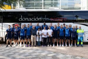 Grupo de personas posando frente a un autobús de donación de sangre