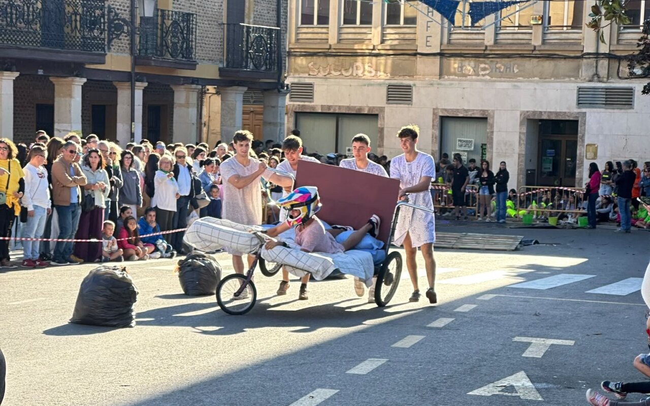Participantes en la carrera de camas en Saldaña, vestidos con pijamas y casco.