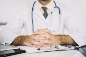Primer plano de un médico con un clipboard en la mesa