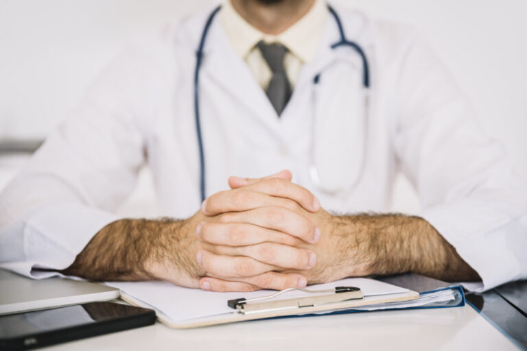 Primer plano de un médico con un clipboard en la mesa