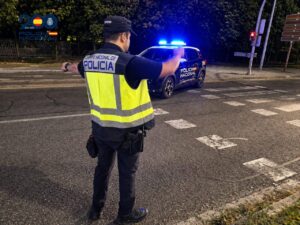 Agente de policía deteniendo un vehículo en Palencia durante la noche.
