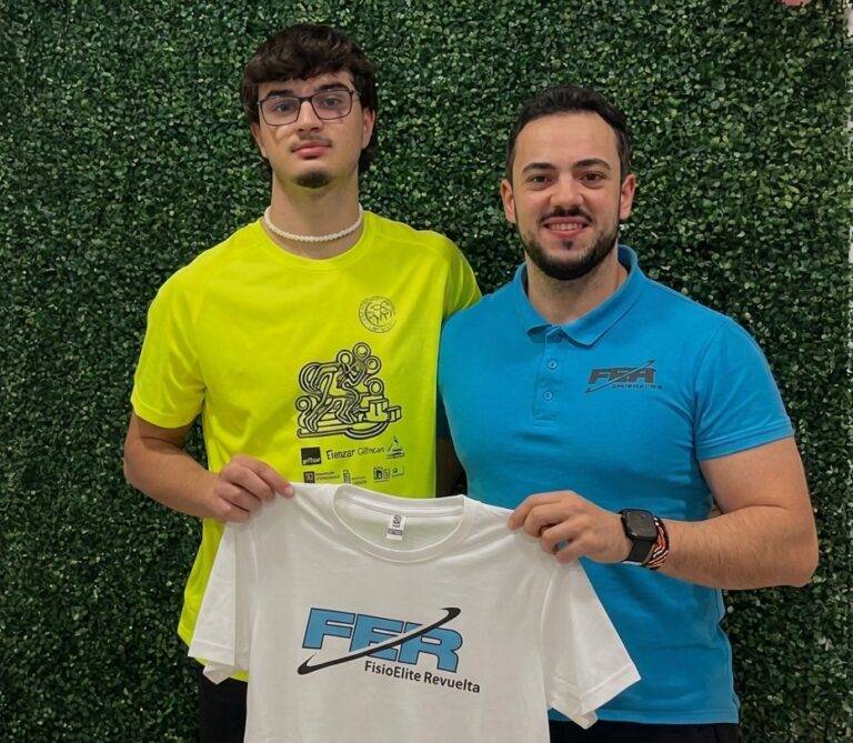 Dos personas sosteniendo una camiseta de FisioÉlite Revuelta en un entorno deportivo