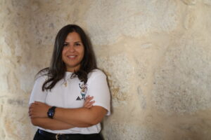 Mujer sonriendo con camiseta de oveja en pared de piedra