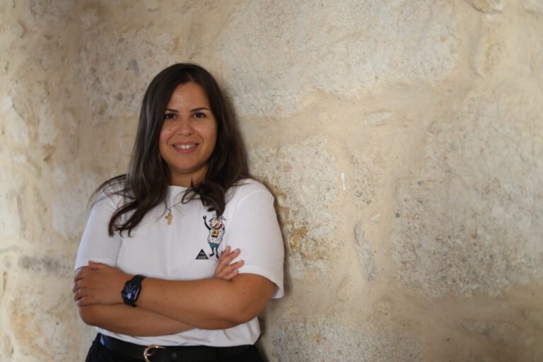 Mujer sonriendo con camiseta de oveja en pared de piedra