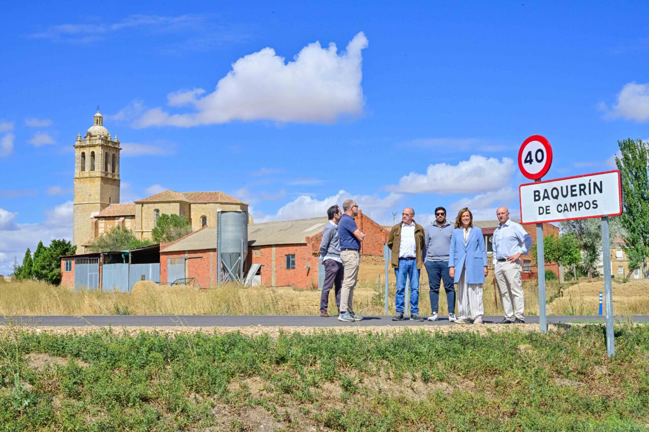 Grupo de personas junto a un cartel de Baquerín de Campos y una iglesia