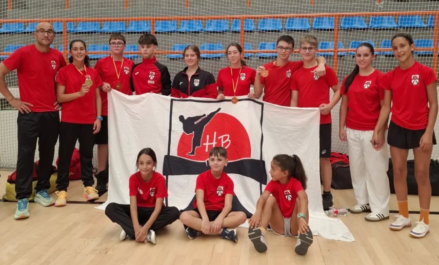 Grupo de jóvenes karatecas con medallas y bandera del club en Salamanca