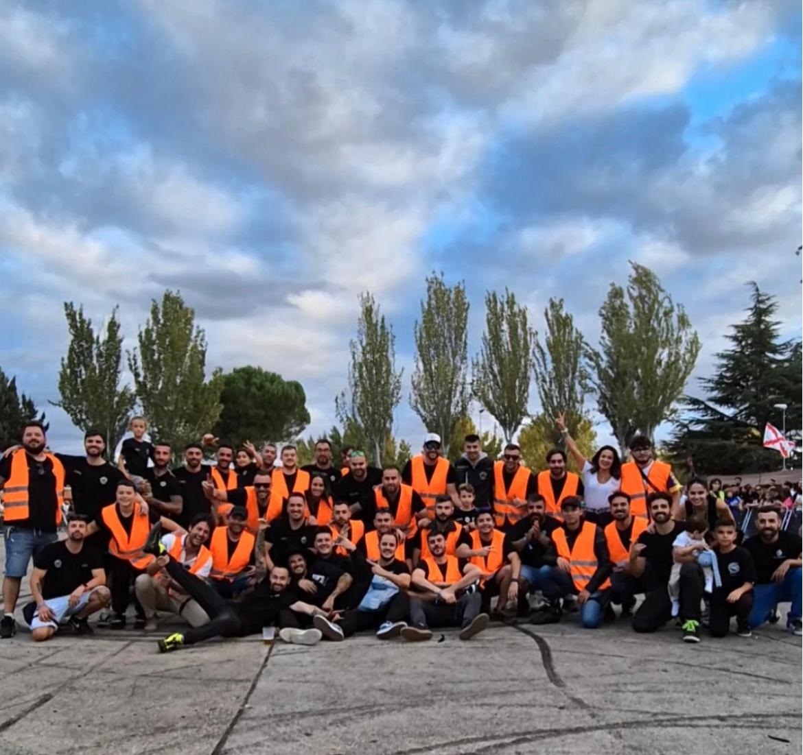 Grupo de personas en evento de motos con chalecos naranjas