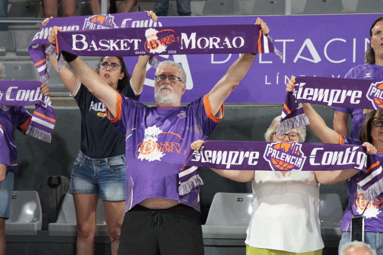Aficionados sosteniendo bufandas en un partido de baloncesto en Palencia.