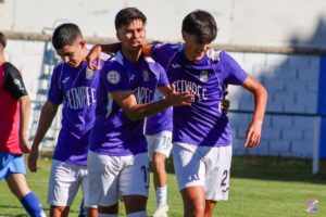 Jugadores celebrando un gol en un partido de fútbol juvenil.