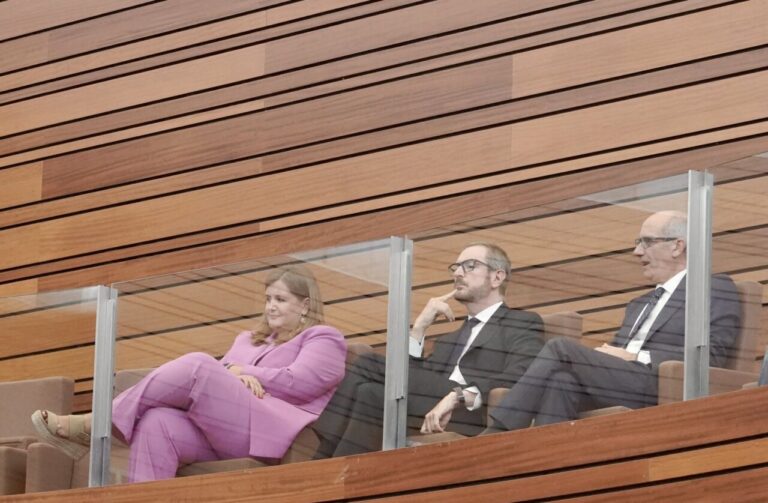Tres senadores en un pleno, observando atentamente desde sus asientos.
