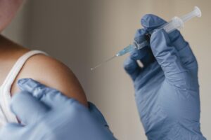 Doctor administrando vacuna a un niño con guantes azules