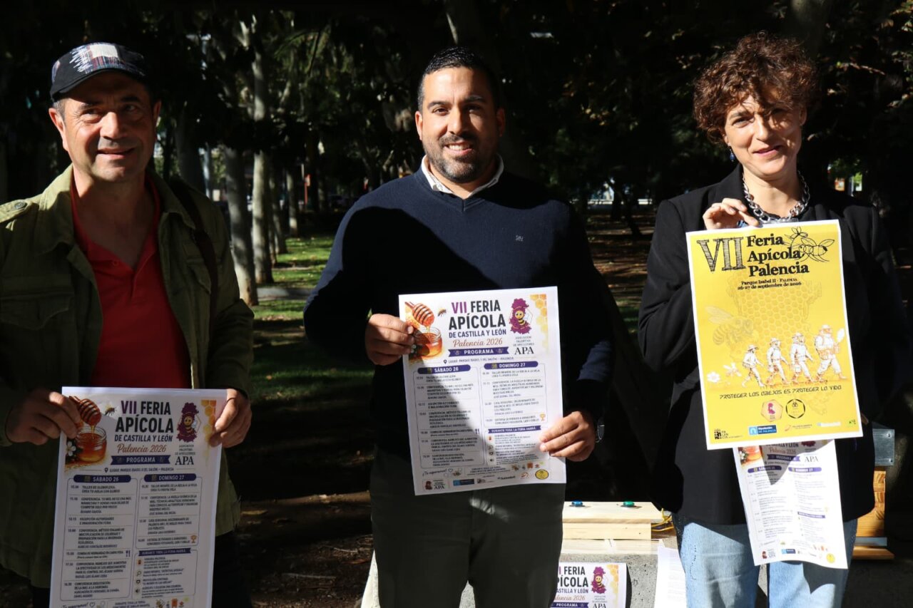 Tres personas sosteniendo carteles de la VII Feria Apícola de Palencia