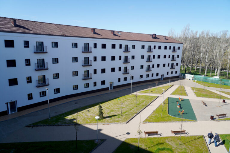 Edificio de viviendas de protección pública en Castilla y León con áreas verdes.