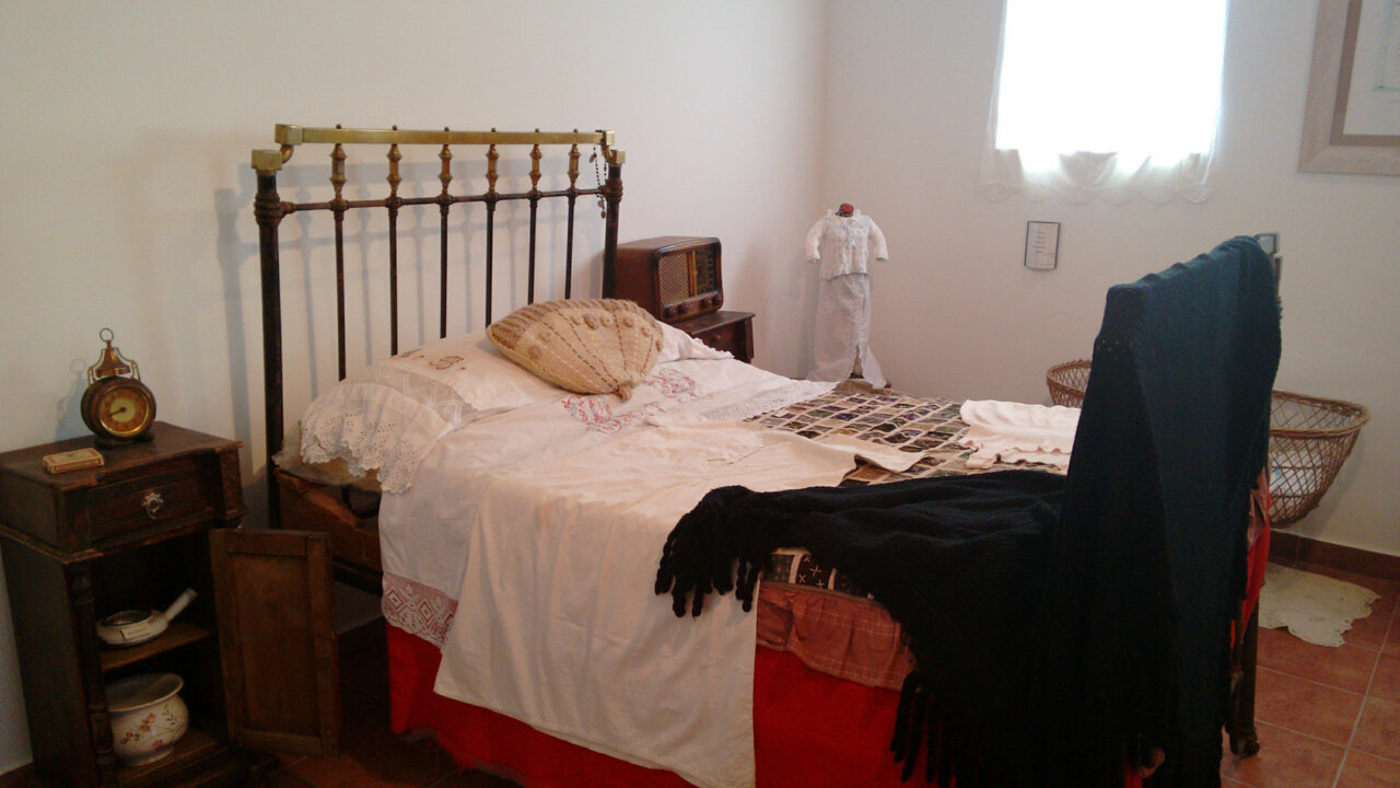 Habitación tradicional con cama, ropa de cama y objetos antiguos