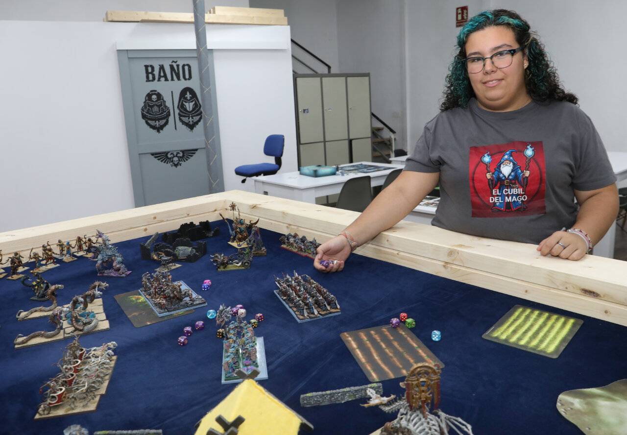 Joven en tienda de juegos de mesa con miniaturas y dados