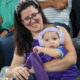 Mujer sonriente con un bebé en un partido de baloncesto